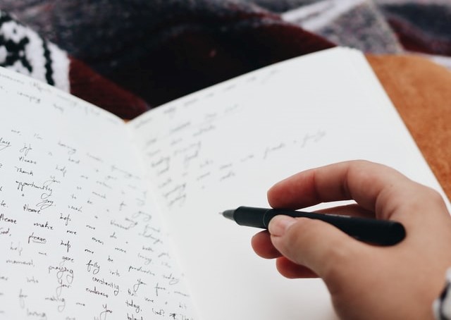 weibliche Hand schreibt mit schönem Stift in liniertes Notizbuch