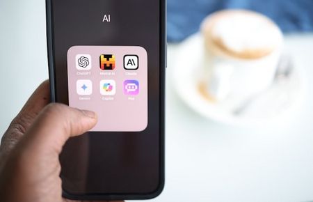 Hand hält Handy mit AI-Tools auf dem Bildschirm