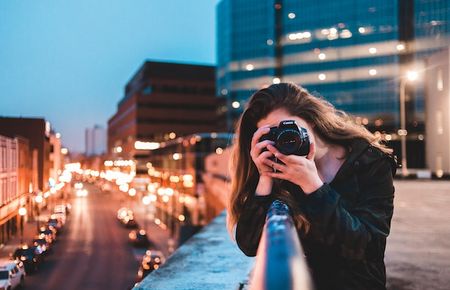 Frau hält eine Fotokamera in der Hand.