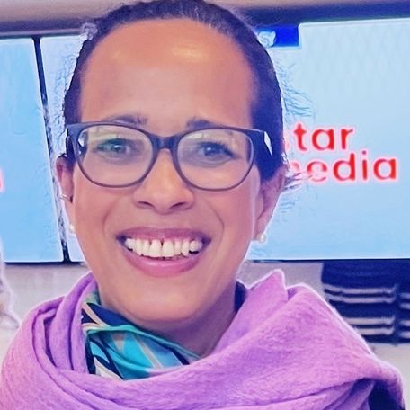 lachende Frau mit zurückgekämmten Haaren, Brille und violettem Schal