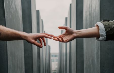 von links und von rechts sieht man zwei Unterarme, deren Fingerspitzen sich leicht berühren