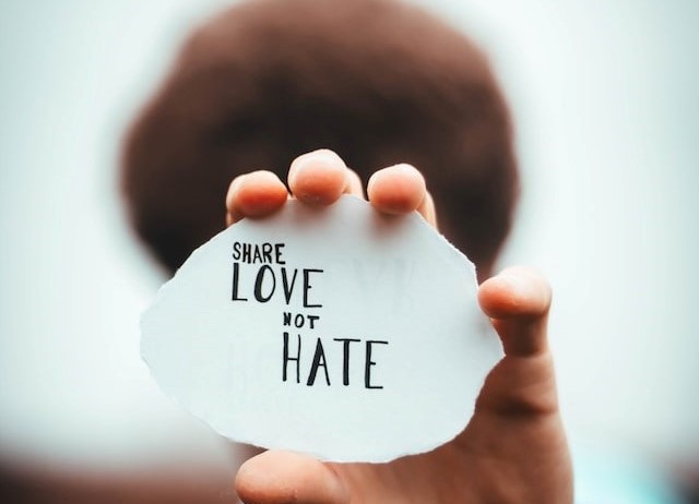 poc hält Schild mit message "share love not hate"