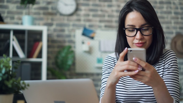 Frau im Büro am Schreibtisch schau auf Handy Display